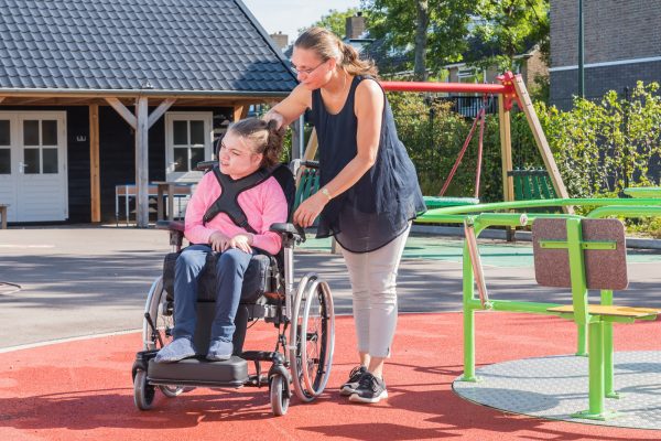 A disabled child in a wheelchair being cared for by a voluntary care worker