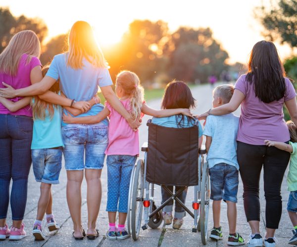 Rear view group of people supporting young women on a wheelchair